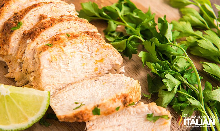 sliced chicken with lime and parsley on cutting board
