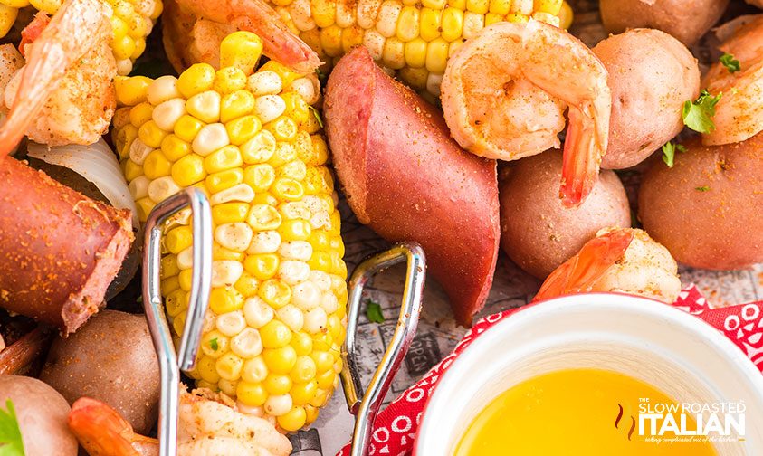 tongs grabbing corn from low country boil