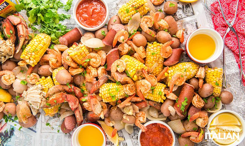 low country boil spread onto newspaper with dipping sauces