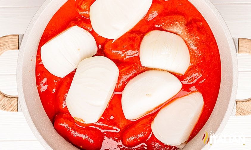 canned tomatoes and onion halves in pot