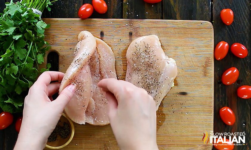 sprinkling salt and pepper on butterflied chicken