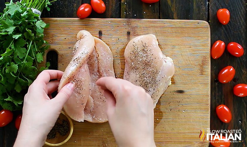 sprinkling salt and pepper on butterflied chicken