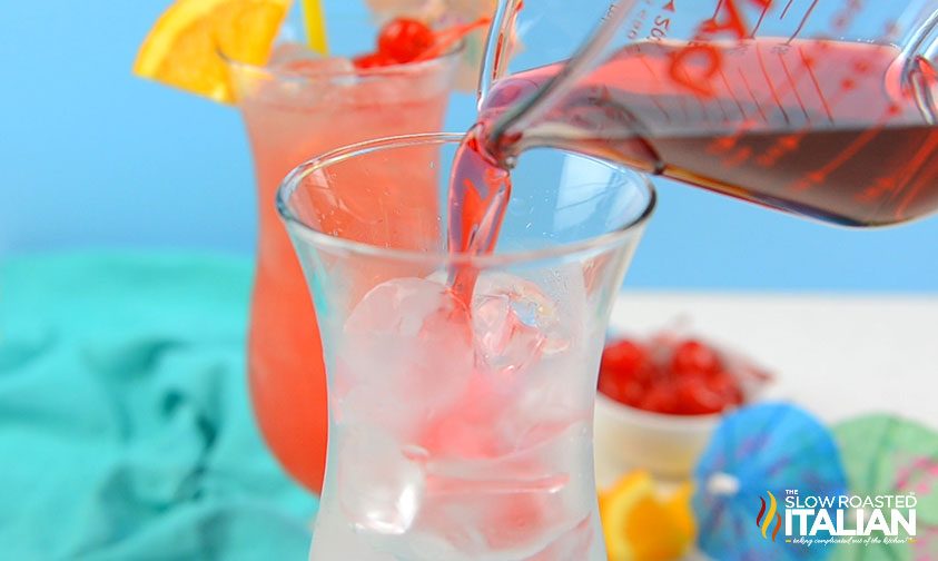 pouring cranberry juice into hurricane glass