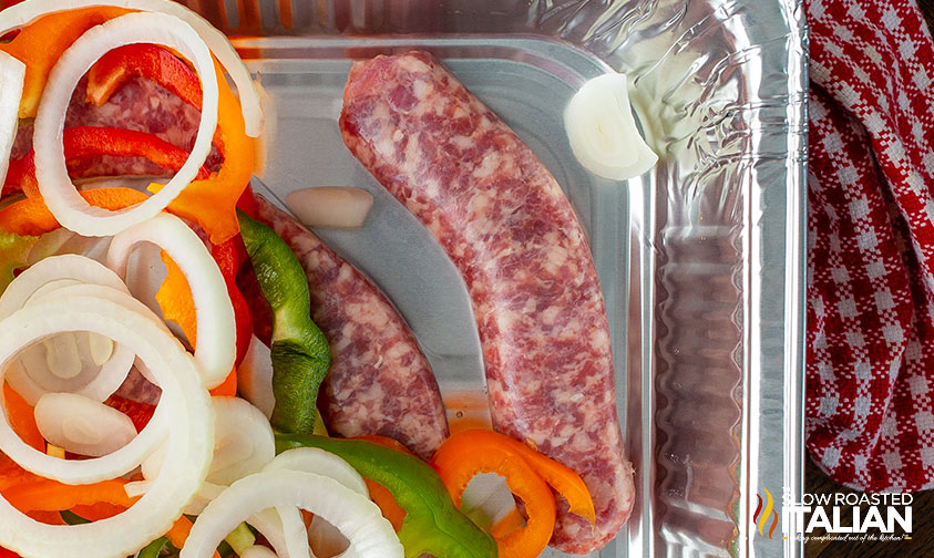 close up: bratwurst, peppers, and onions in a foil pan