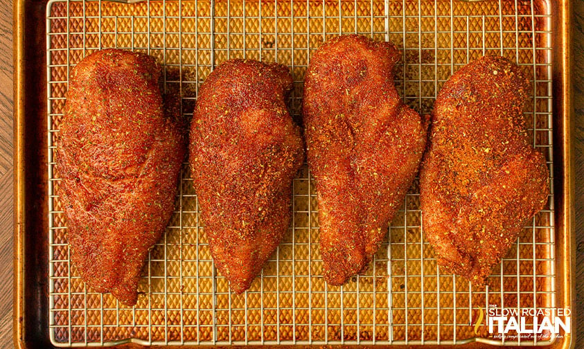 chicken breasts coated in dry rub on a wire rack