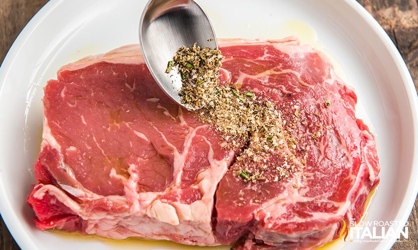 spooning seasoning over ribeye steak