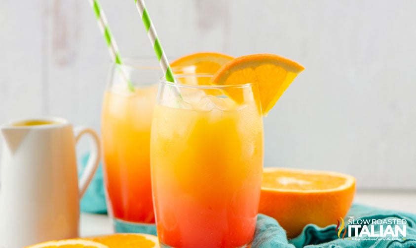 two tequila sunrise drinks with straws and orange slices