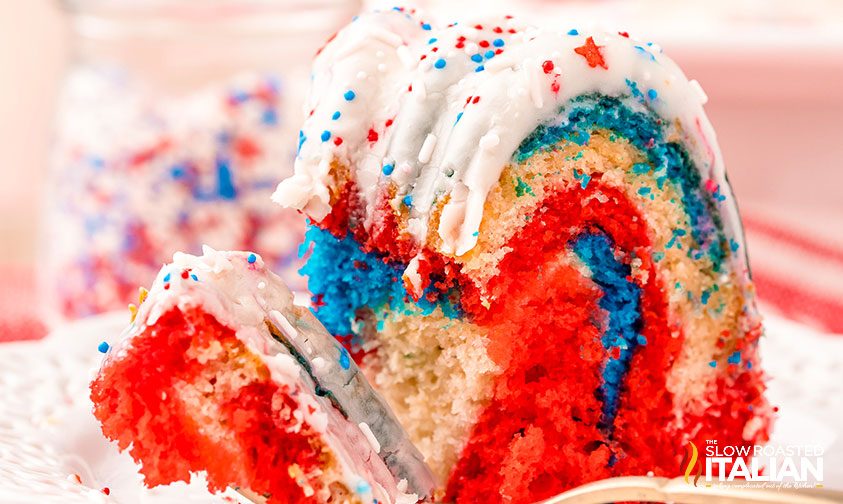 slice of red white and blue bundt cake with frosting and sprinkles