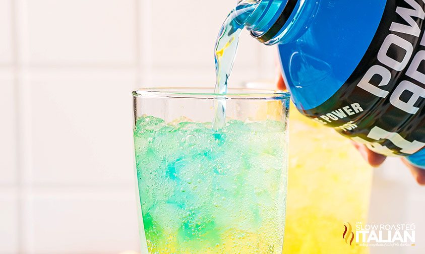 pouring blue Powerade into glass with Sprite and Mountain Dew