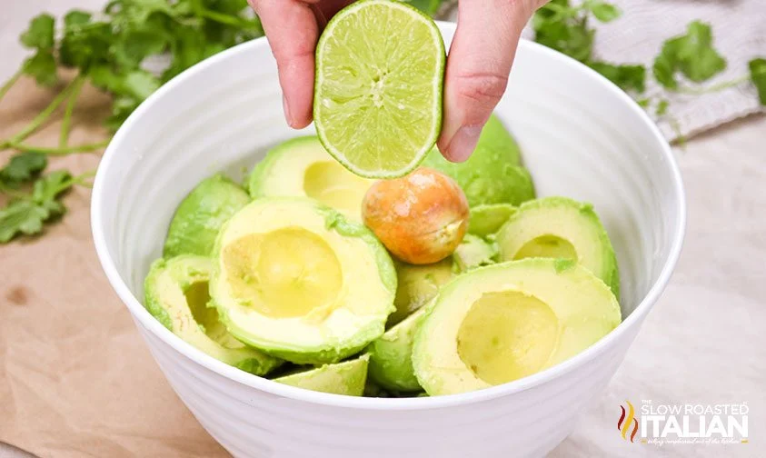 squeezing fresh lime over avocados in bowl