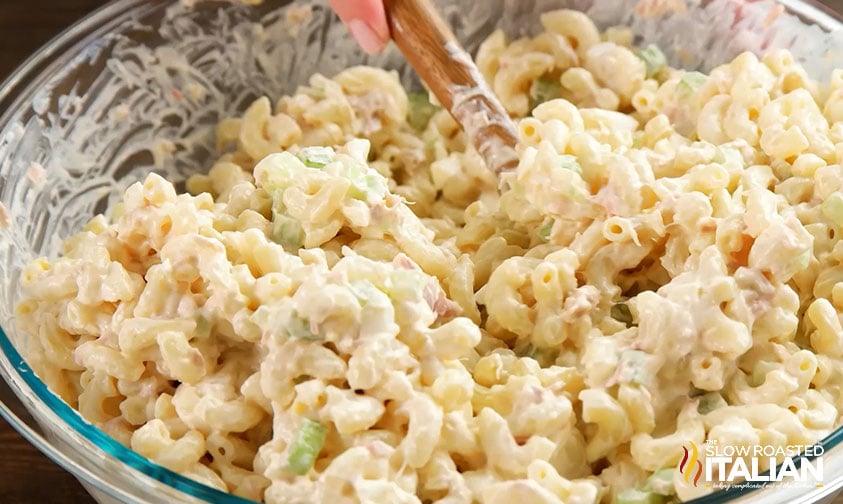 stirring creamy macaroni salad in bowl