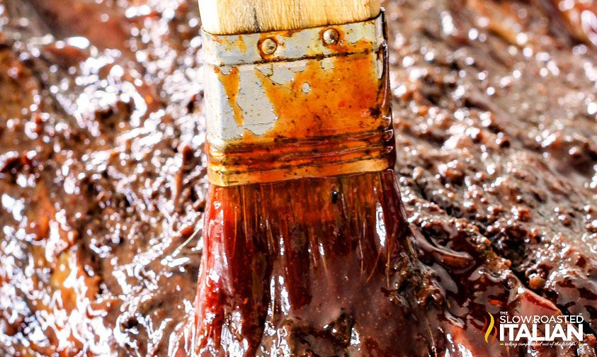 brushing bbq sauce on beef brisket