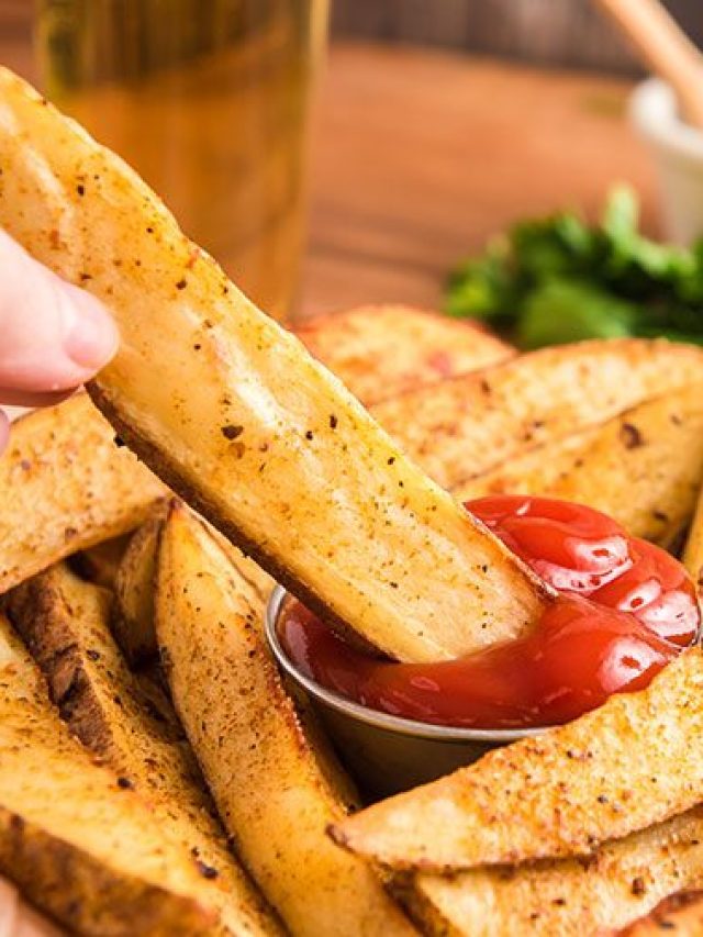 dipping seasoned potato wedges in ketchup