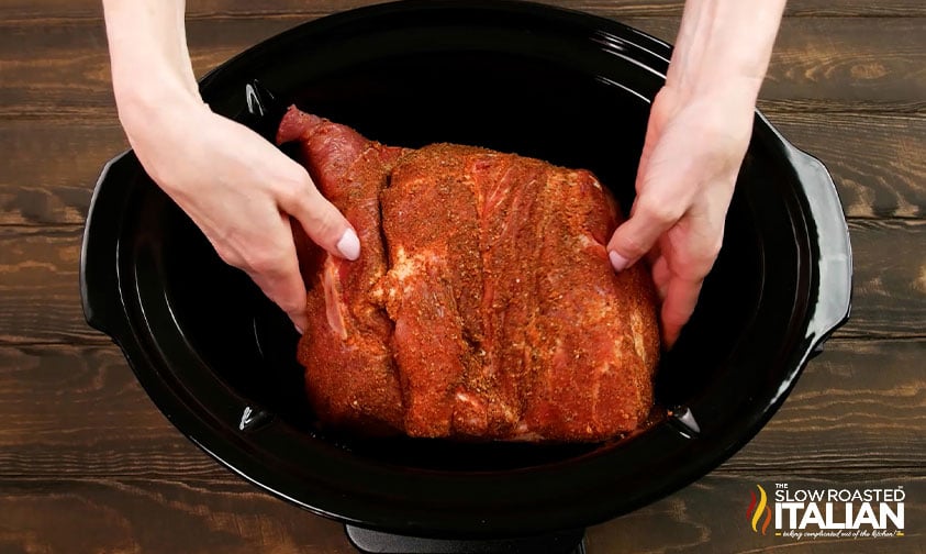 placing seasoned pork shoulder in crock pot