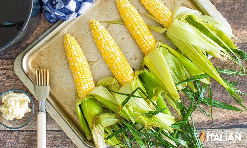 corn on the cob with husks peeled back waiting to be seasoned