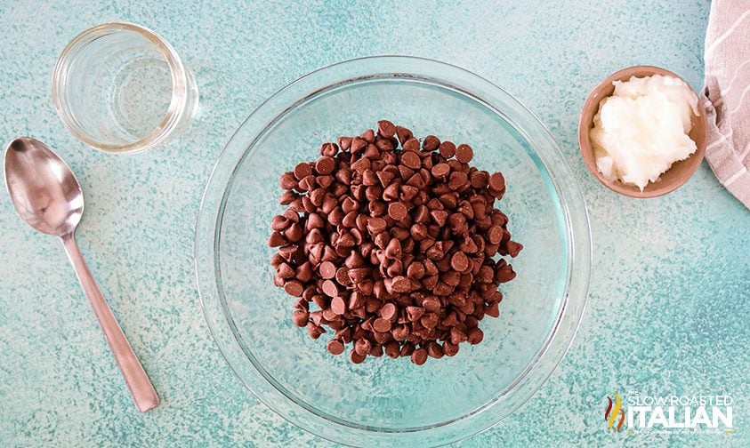 bowls of chocolate chips and coconut oil with an empty mason jar and spoon