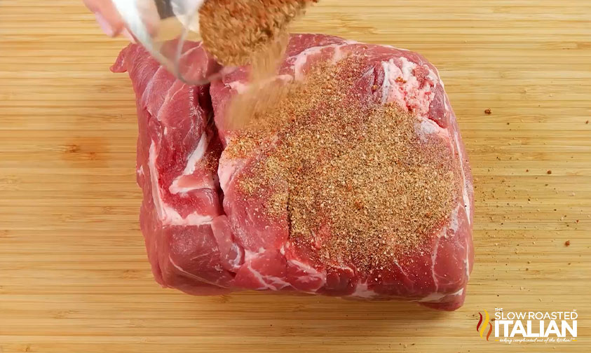 sprinkling spice mix over pork butt