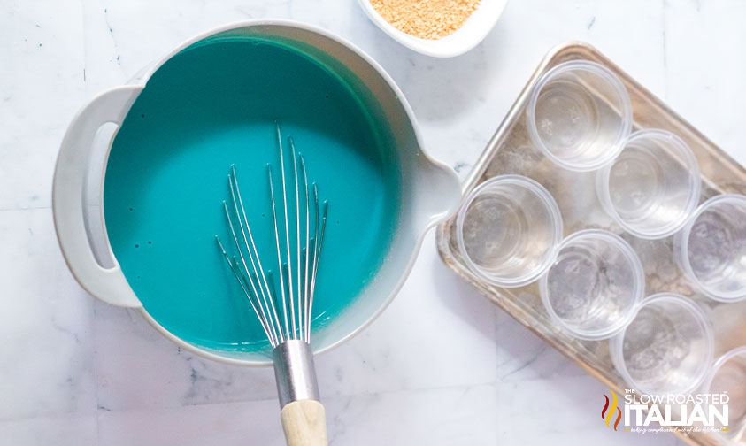 whisked blue pudding shot base next to tray with plastic shot cups