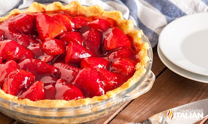 whole strawberry pie next to plates