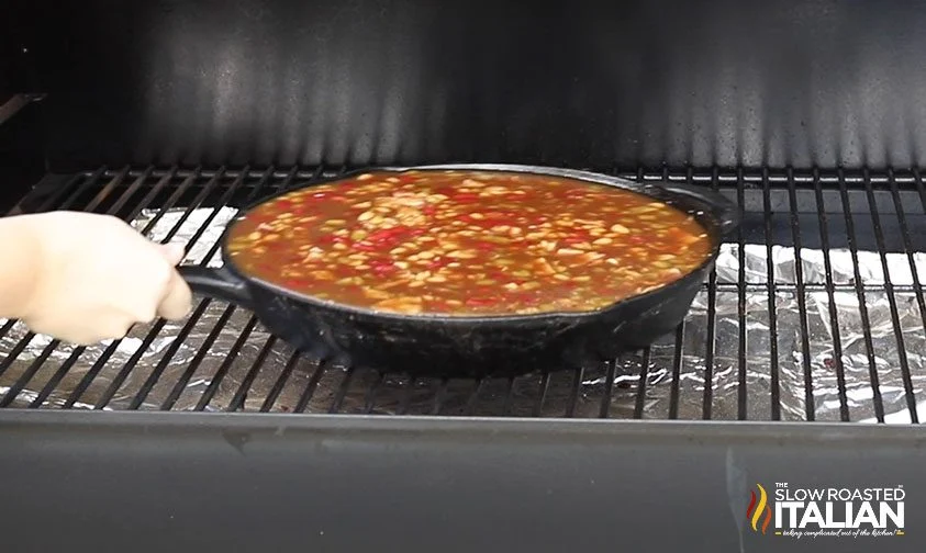 placing cast iron pan of beans in smoker