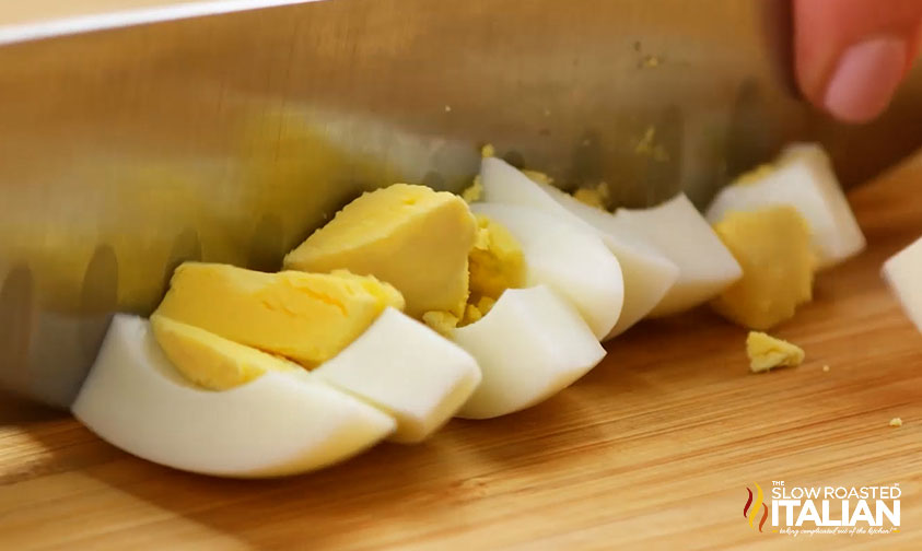 chopping hard boiled eggs with a large knife