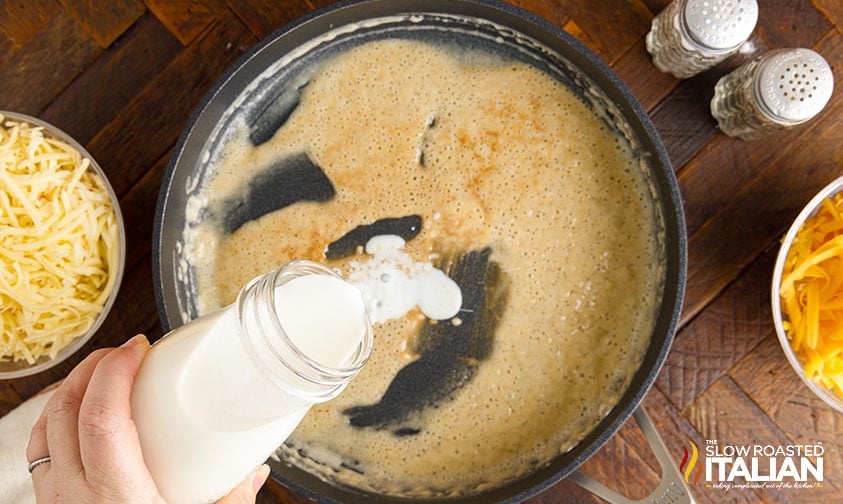 pouring milk into roux to make cheese sauce