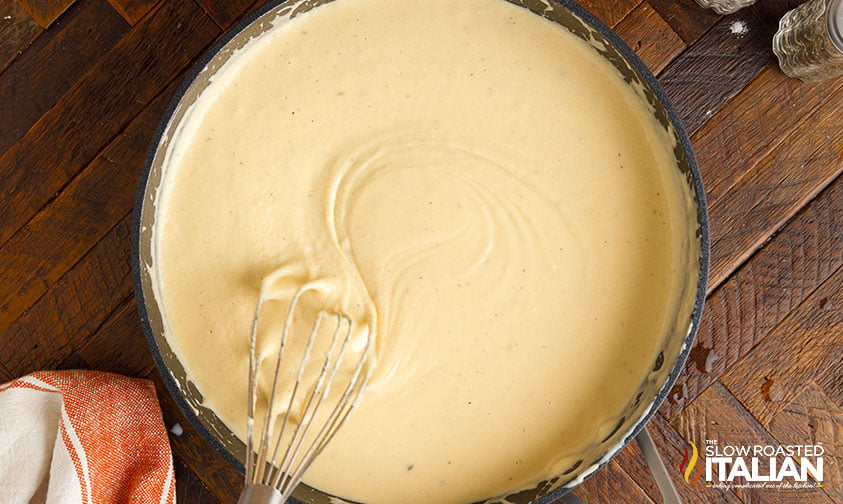 whisking cheese sauce in skillet