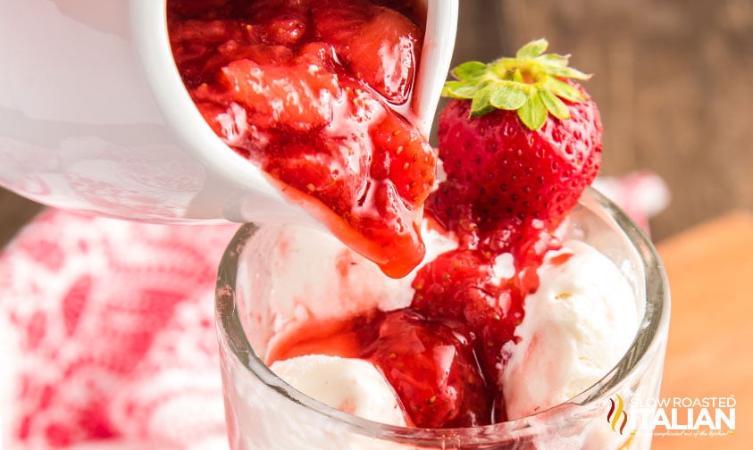 pouring strawberry syrup over vanilla ice cream