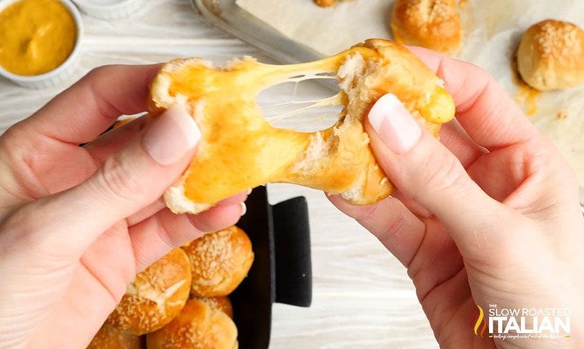 pulling apart stuffed pretzel to show cheese inside
