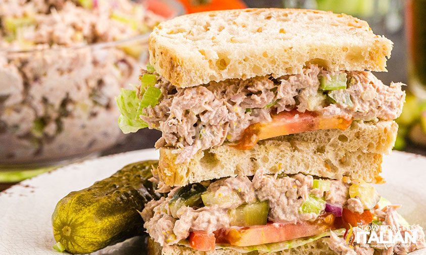 stacked tuna sandwich halves with pickle on the side