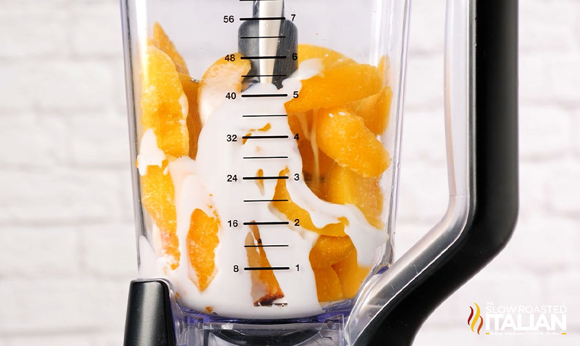 pouring creamer into blender with frozen peaches