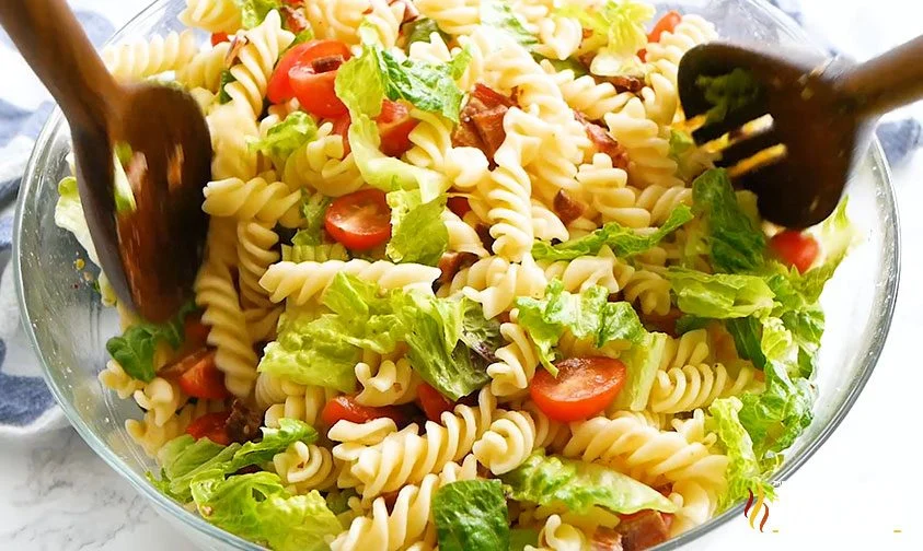 tossing BLT pasta ingredients in bowl