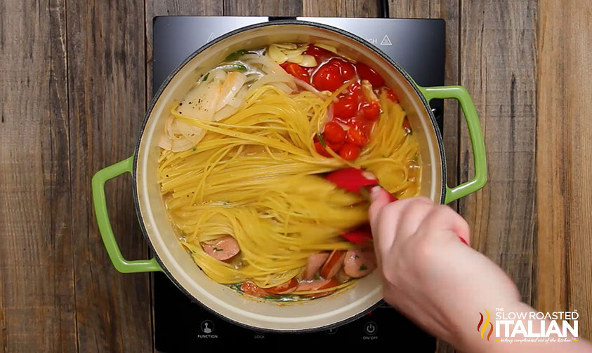 stirring pot of cooked spaghetti with sausage and veggies