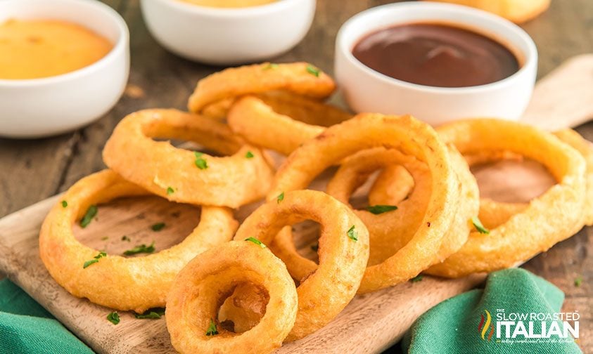 air fried onion rings on serving board with bowls of sauces