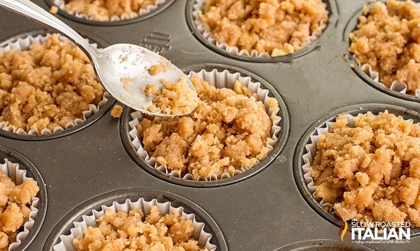adding streusel topping to muffin batter in baking tin