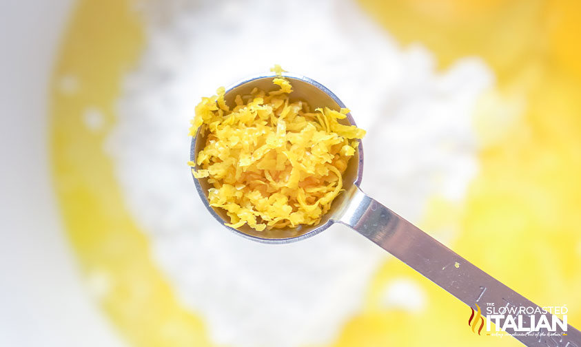 measuring spoon with lemon zest over bowl of batter