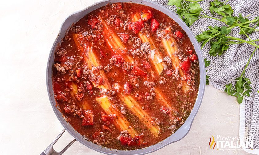 cheese manicotti shells submerged in red sauce in skillet