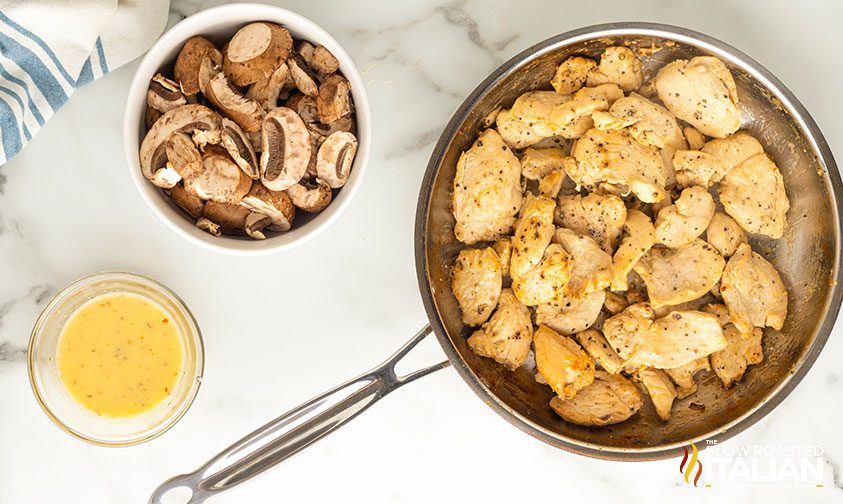 cooked chicken in skillet next to bowl of mushrooms and sauce