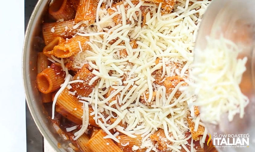 sprinkling cheese over pasta in skillet