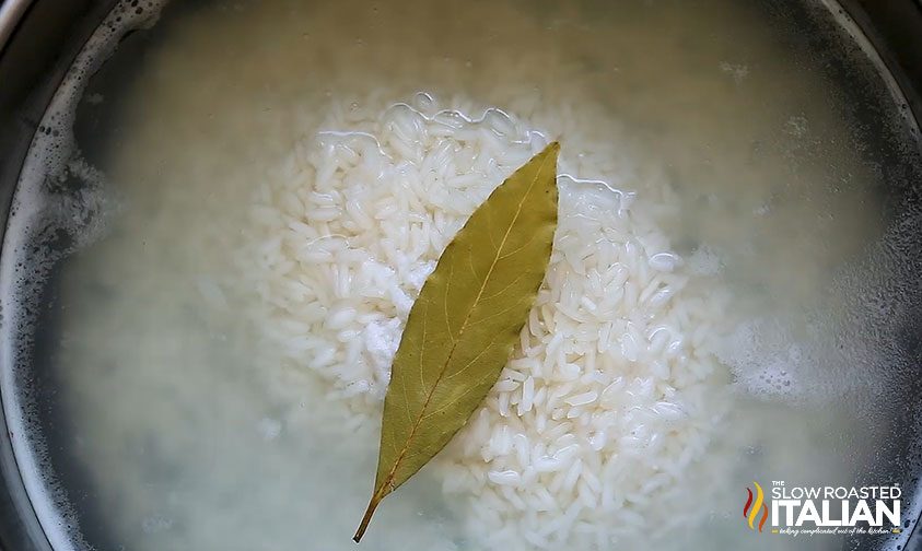 rice submerged in water with bay leaf in pot