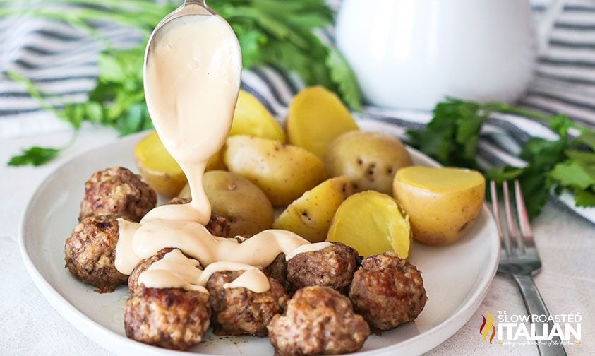 spooning sauce over meatballs with a side of potatoes