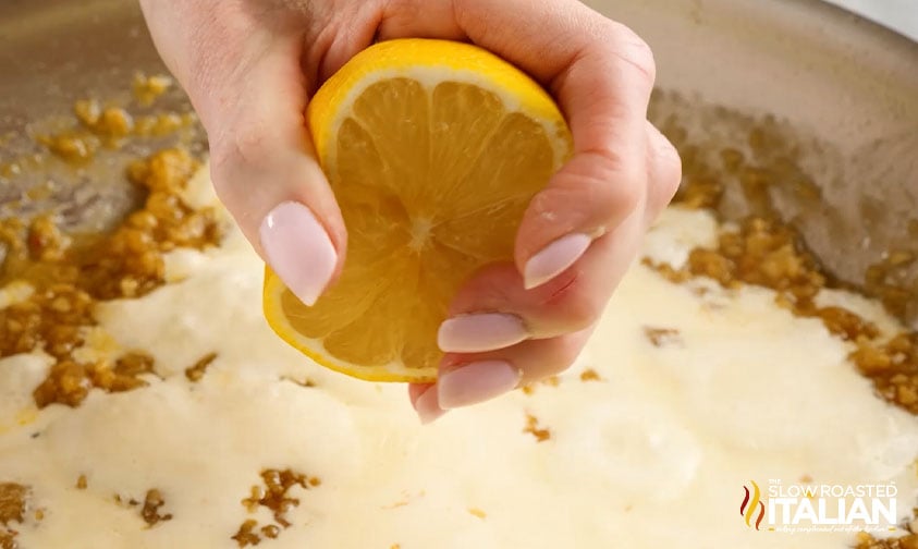 squeezing halved lemon into skillet to make sauce