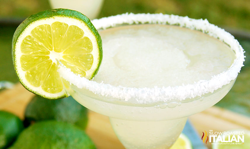 close up: blended margarita with salted rim and slice of lime