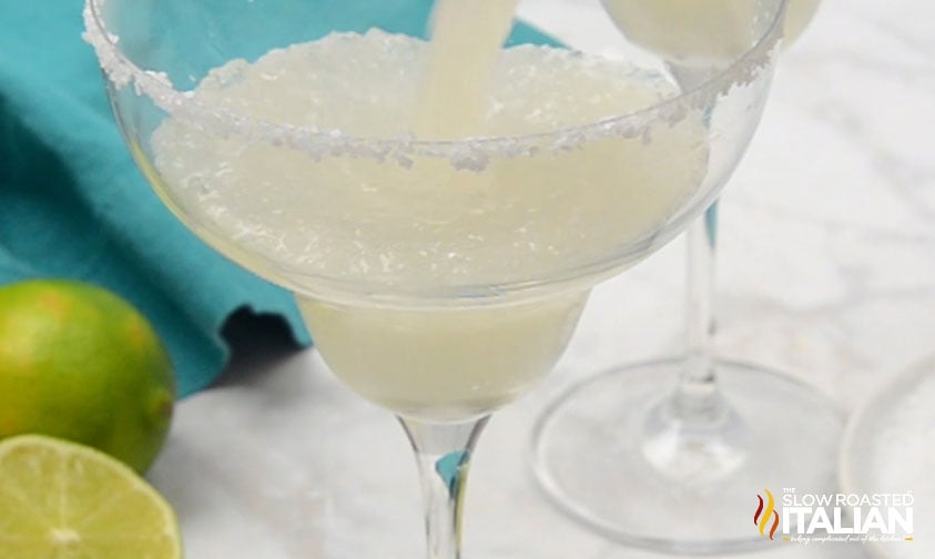 pouring blended margarita into glass with salt rim