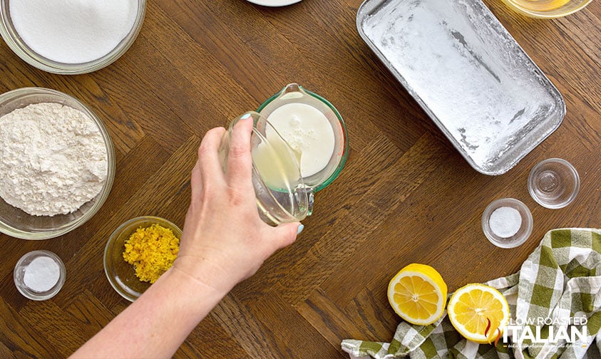 pouring lemon juice into measure cup of milk