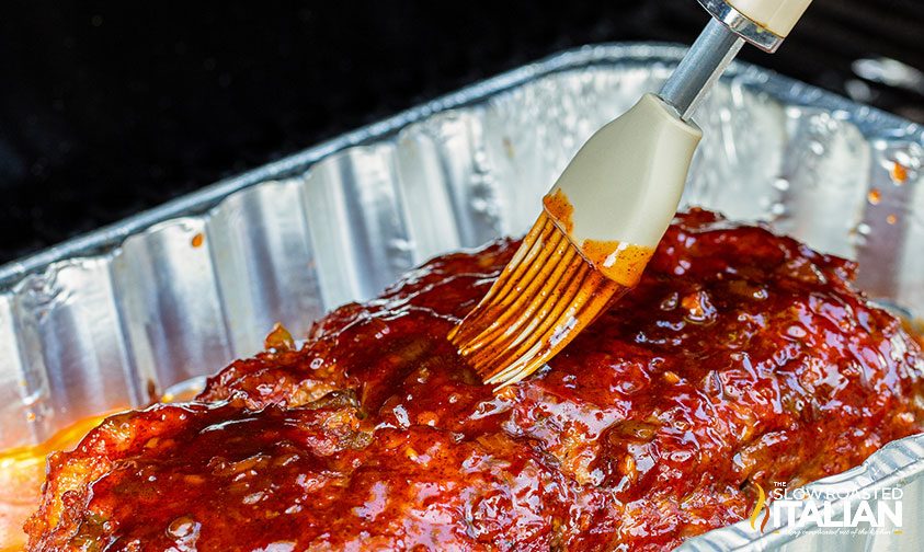 brushing glaze over meatloaf on pellet grill