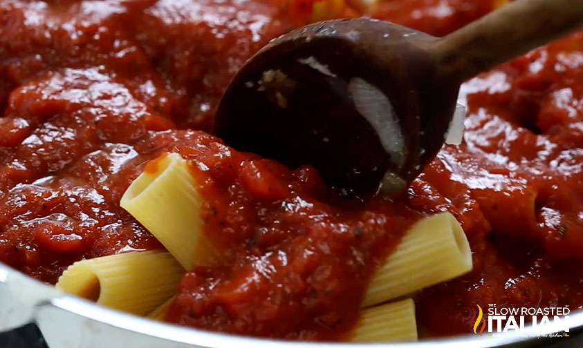 spooning marinara over pasta in skillet