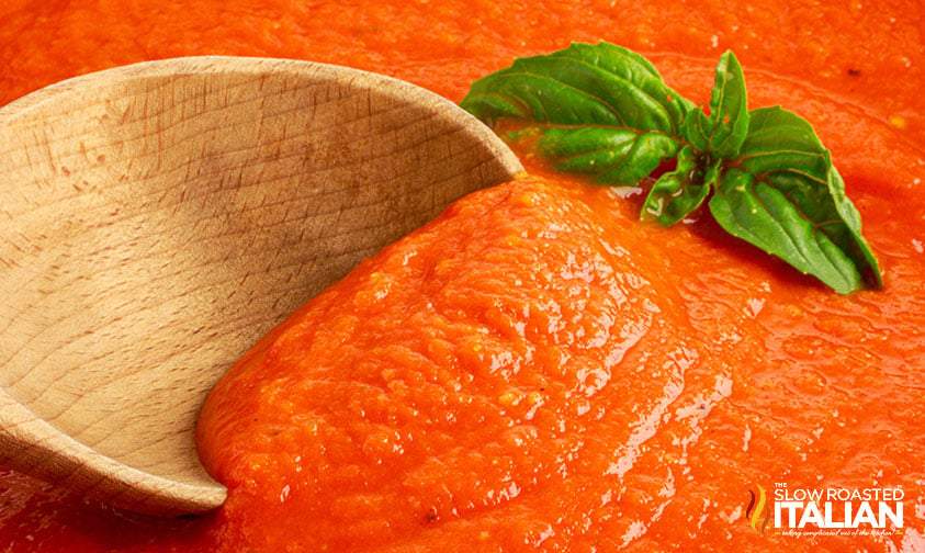 wooden spoon in red sauce with sprig of basil