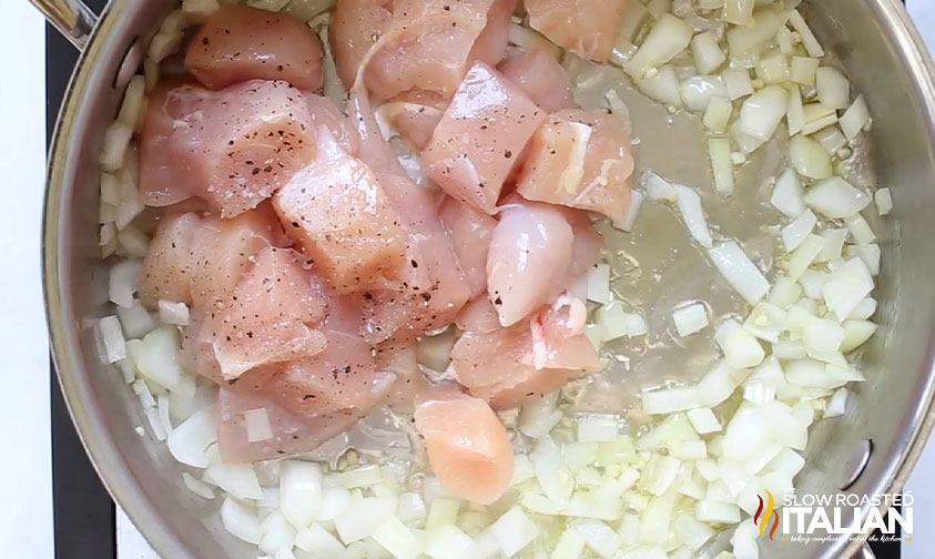 cooking cubed chicken, onion, and garlic in a skillet