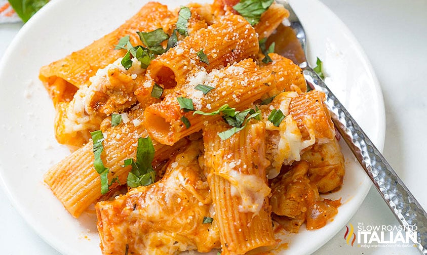 plate of chicken rigatoni topped with cheese and chopped basil